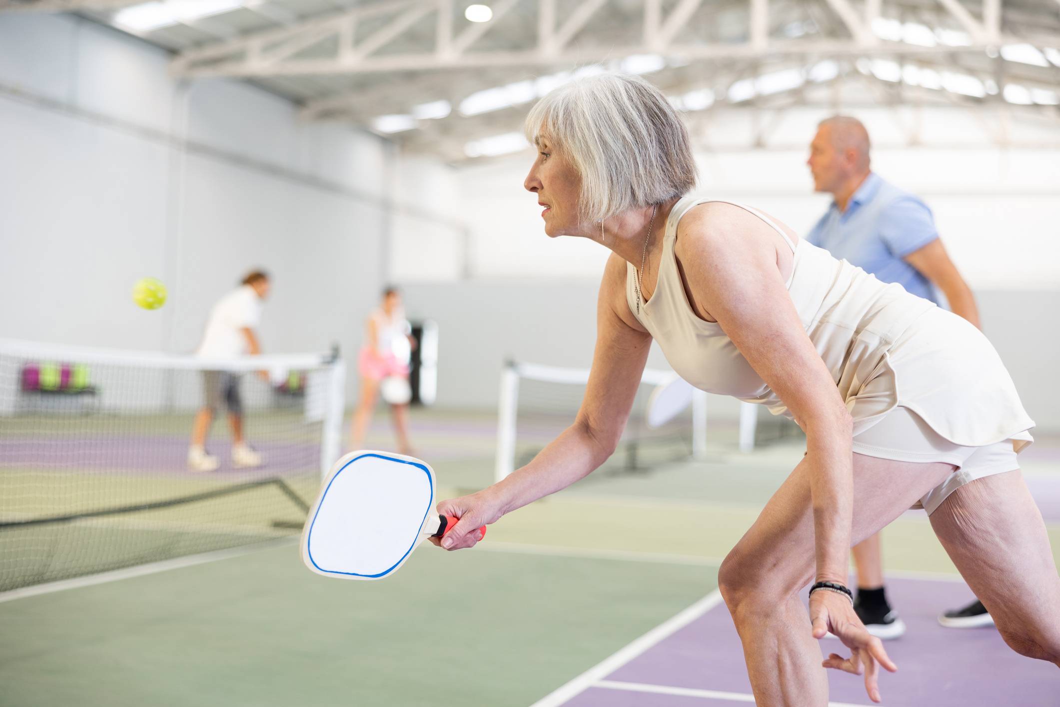 Mature woman playing pickleball doubles
