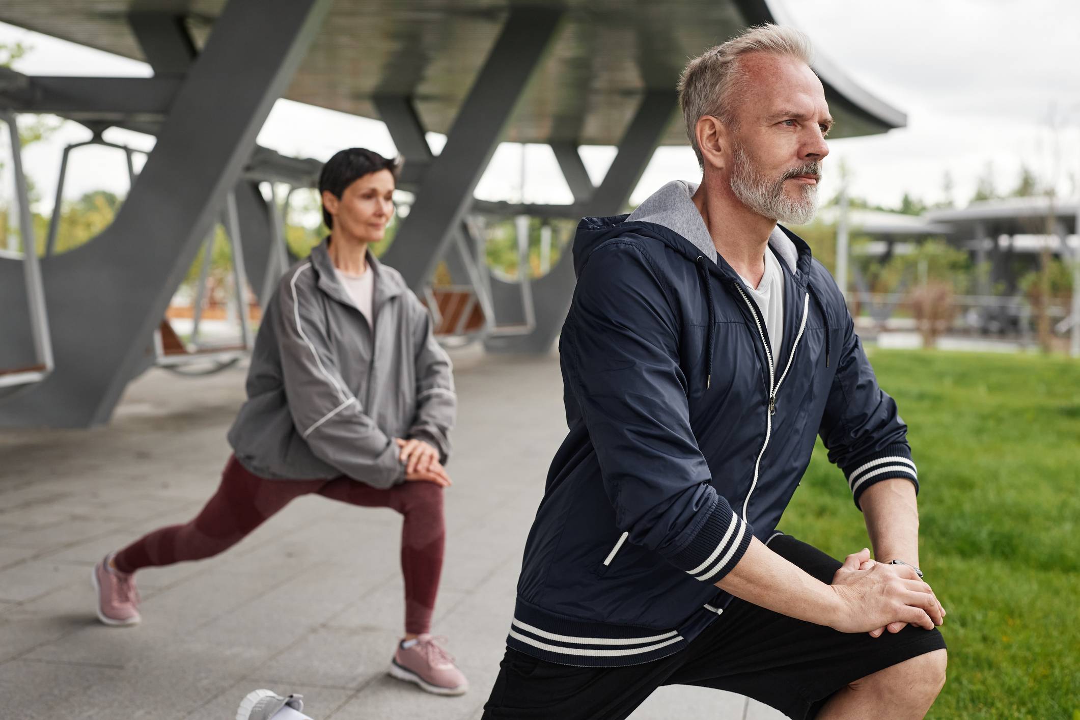 Older couple doing a lunge stretch in outdoor park