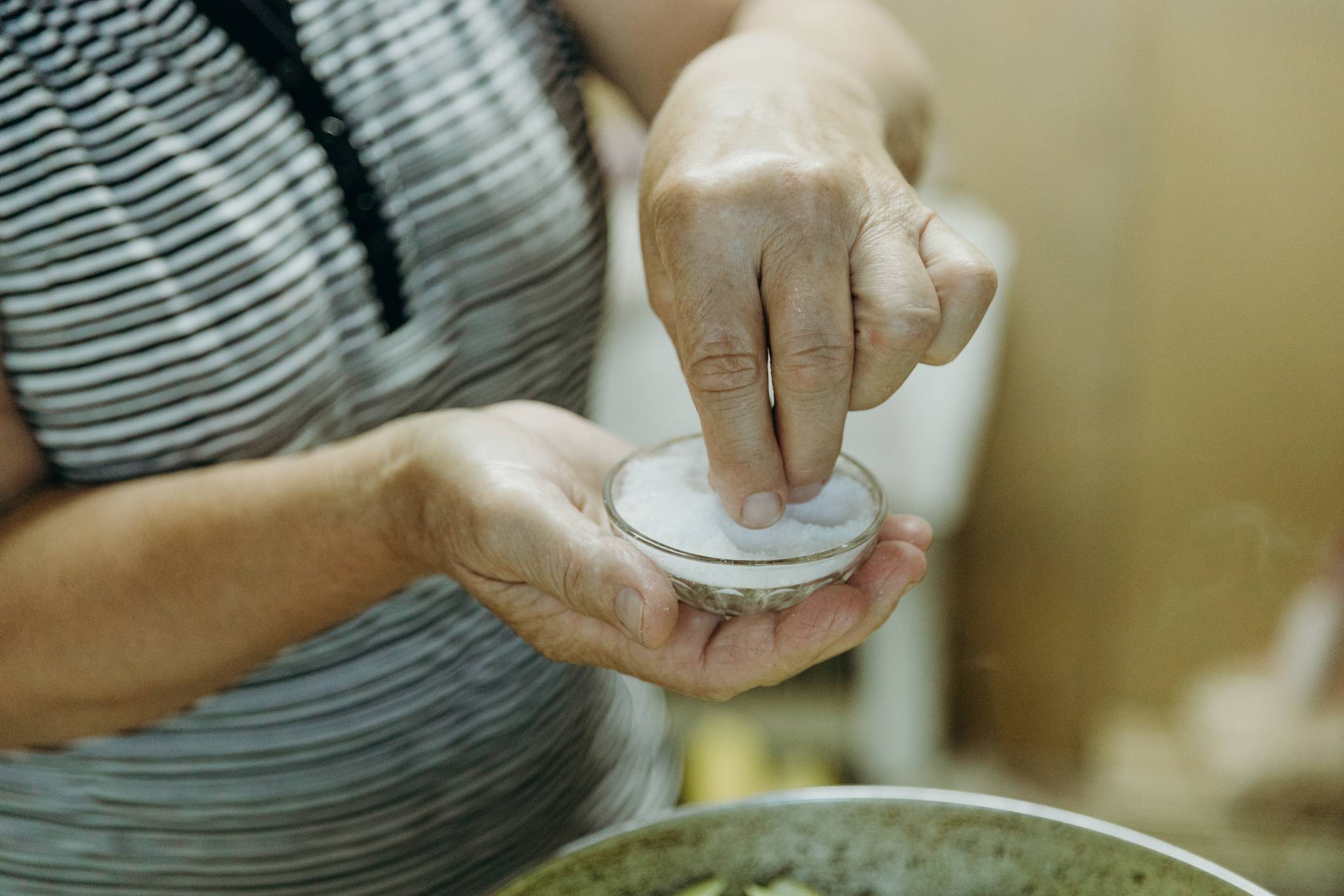 Older woman adding salt to a pot