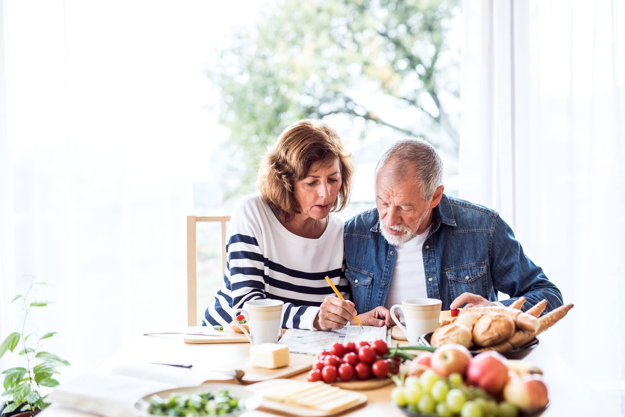 older couple having breakfast and doing a crossword puzzle
