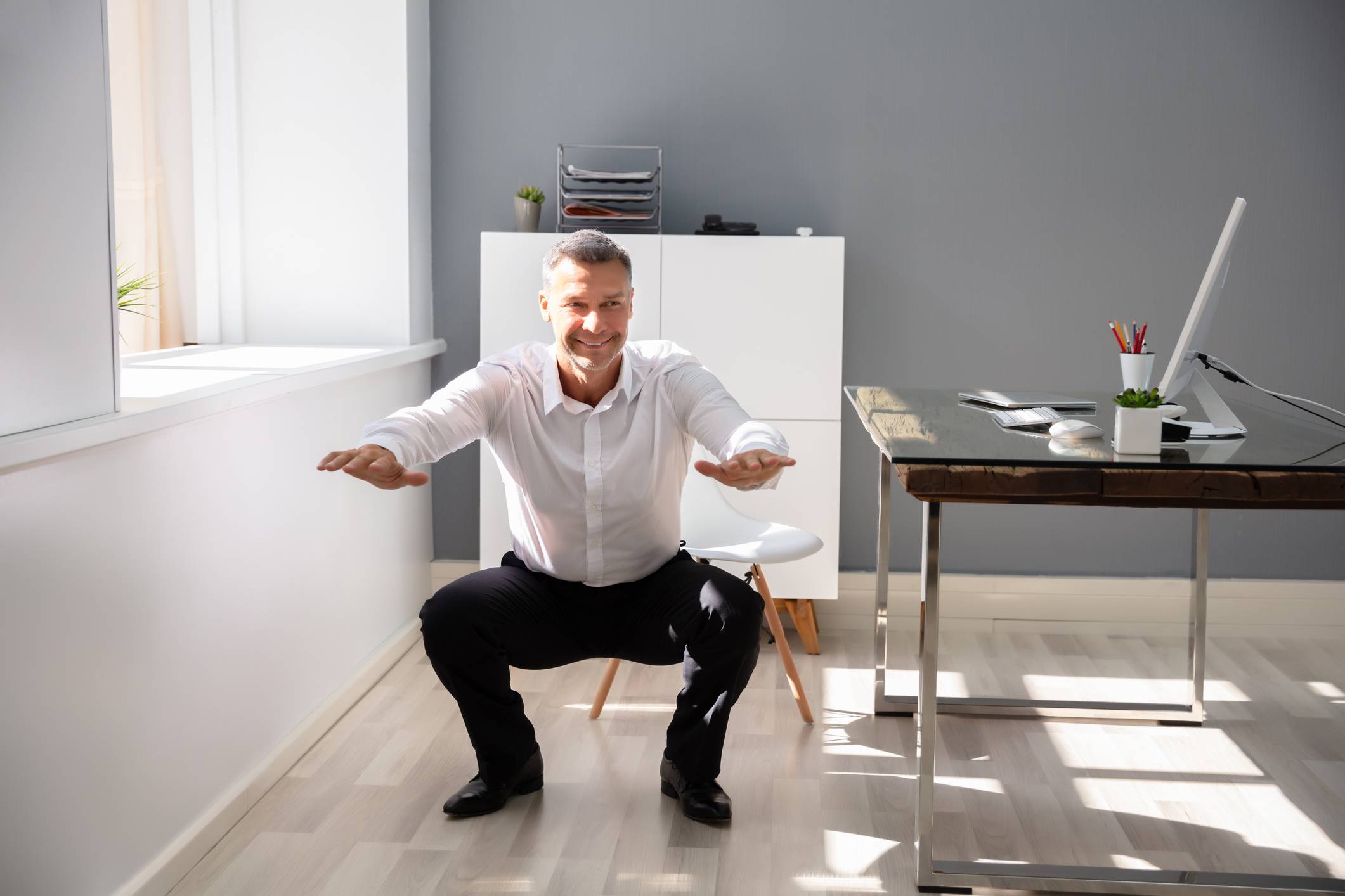 Businessman doing squats at his desk