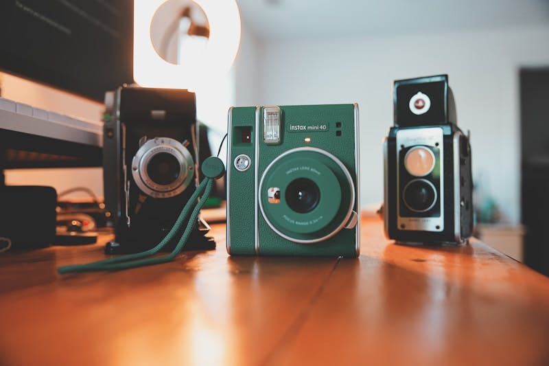 A couple of cameras sitting on top of a wooden table