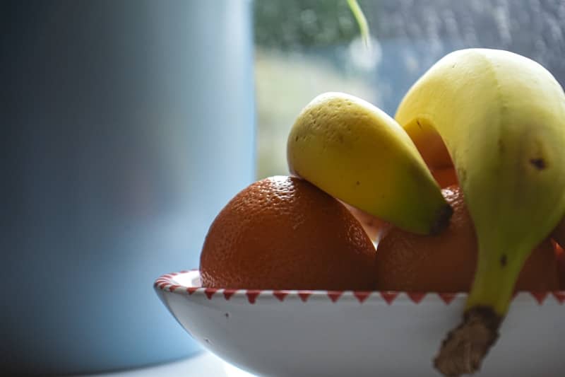 a white bowl filled with oranges and bananas
