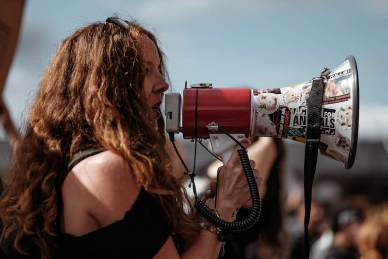 woman using megaphone during daytime protest
