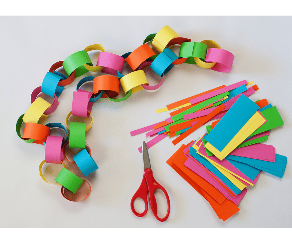 Colorful paper cut into thin strips that are then looped one with another to make a paper chain.