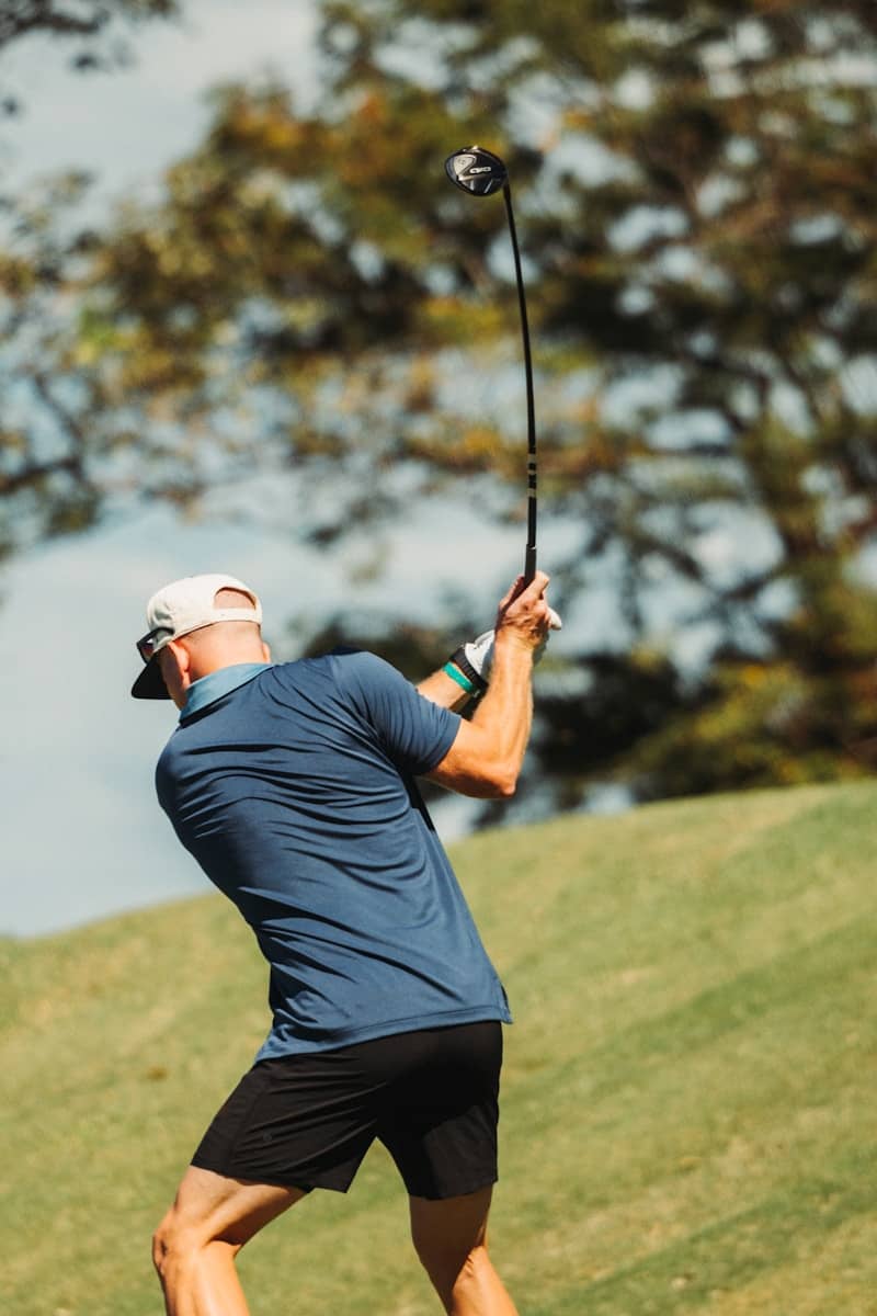 Golfer swinging a club on a grassy hill