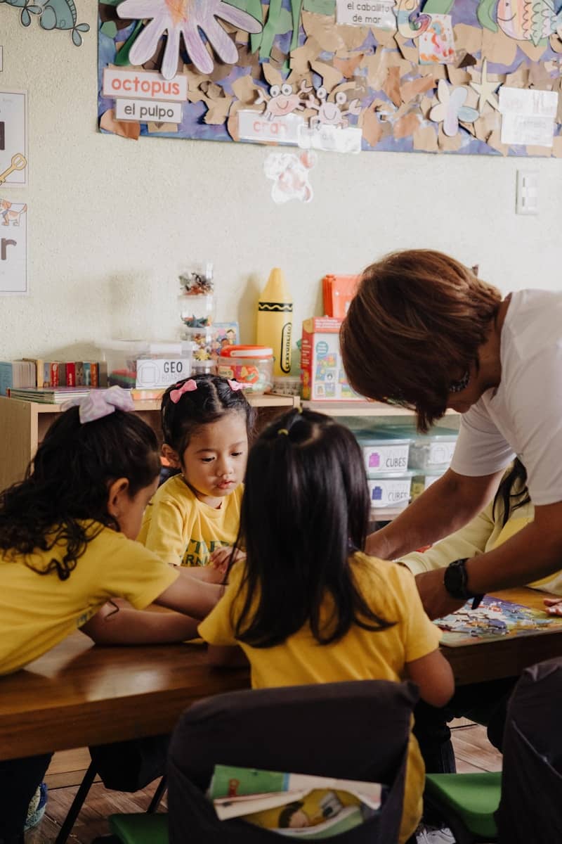 A woman standing over a group of children at a table