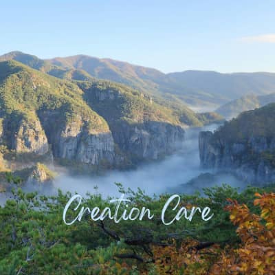 Mountains, River, sky, with green in foreground and the words "Creation Care"
