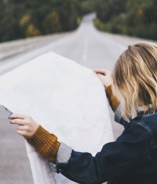 woman looking at map while standing on road