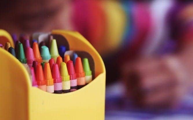 selective focal photo of crayons in yellow box