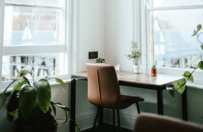 a room with a desk, chair and two windows