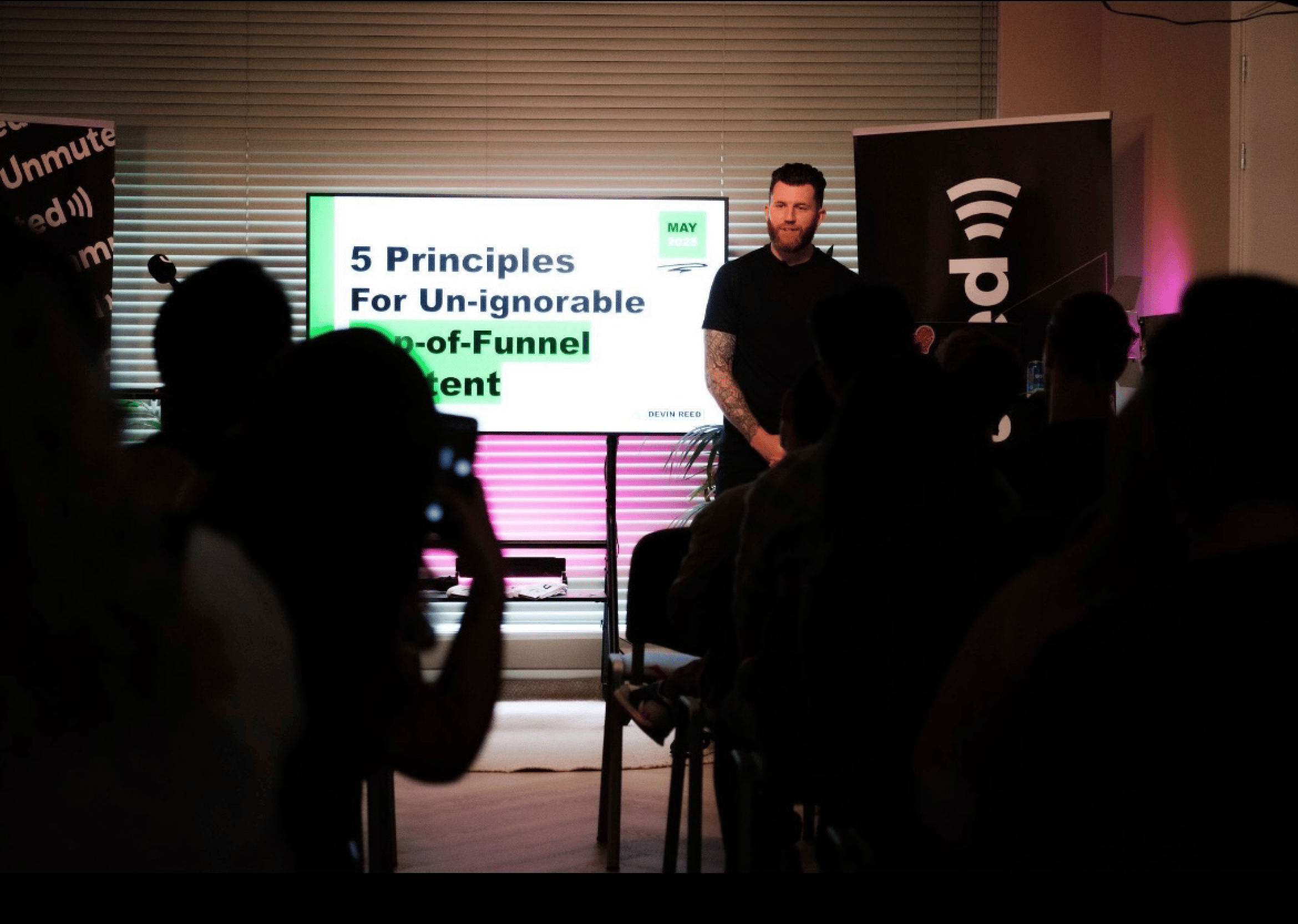 Devin presenting in front of a crowd at the Unmuted Meetup 