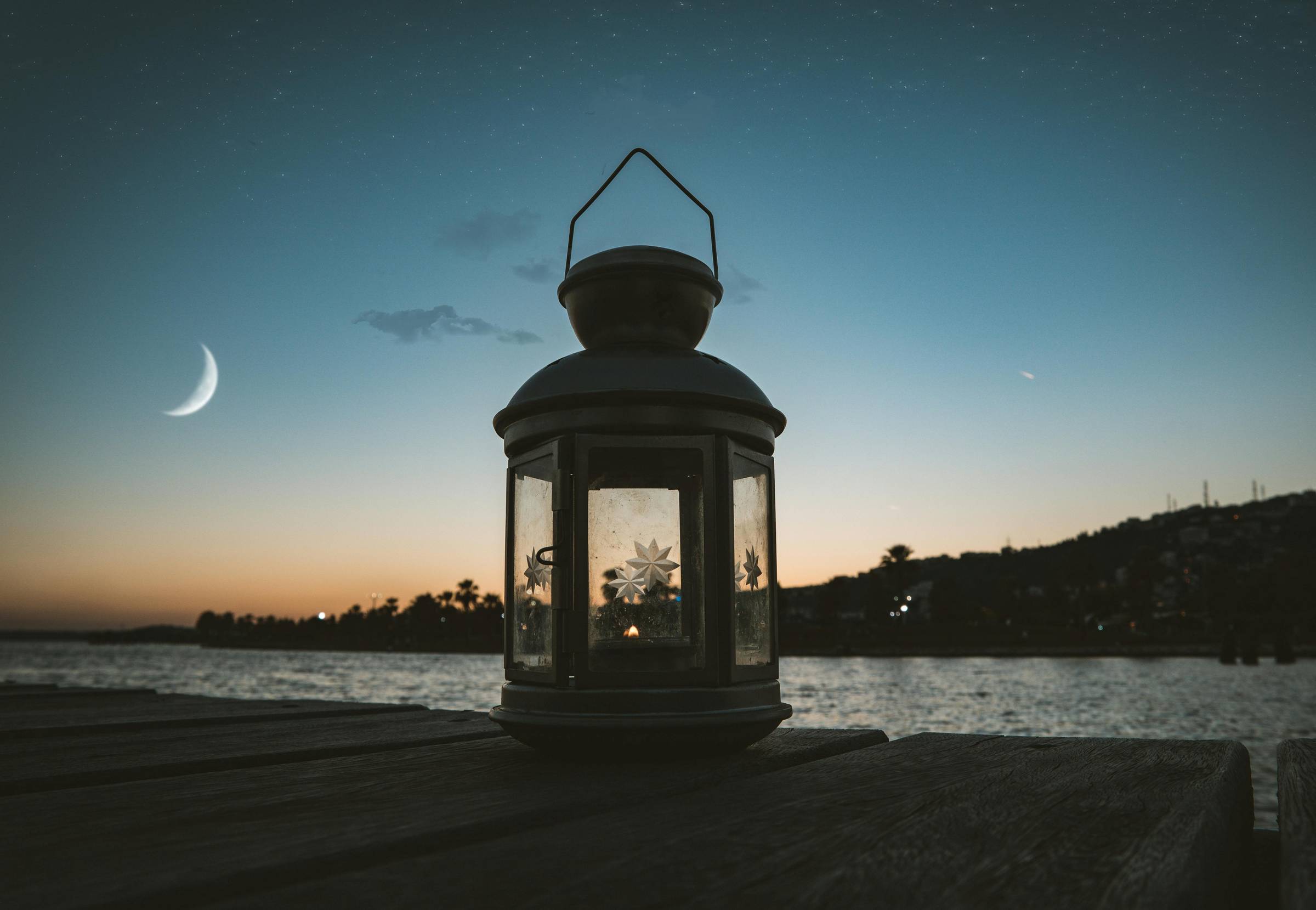 A lantern sitting on a deck in front of a night sky