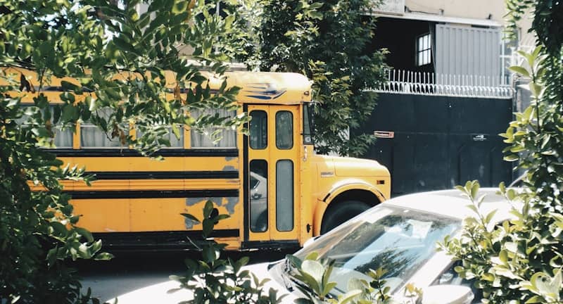 A yellow school bus is parked near a car.
