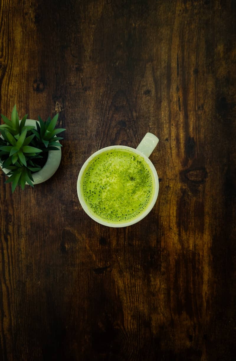 A cup of green tea next to a potted plant