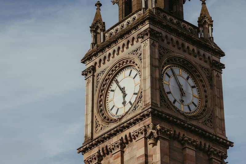Close-up of a historic clock tower against a blue sky.