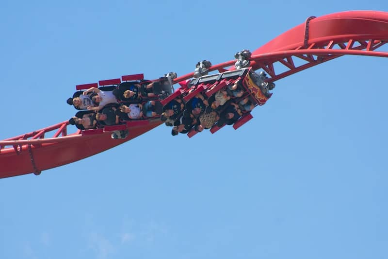 People ride a roller coaster on a sunny day.