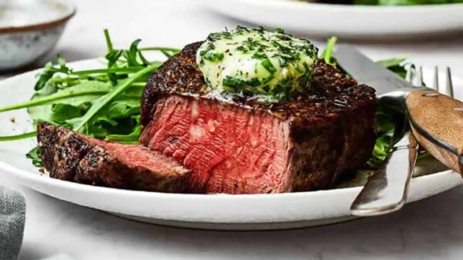 Filet mignon on a plate with steak butter and rocket.