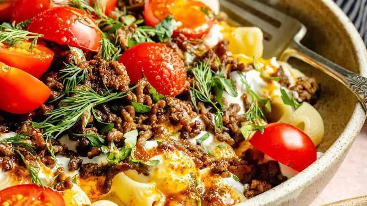A bowl featuring ground beef and rice with fresh vegetables.