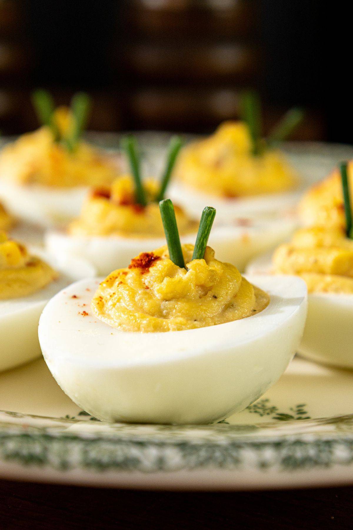 A close up of a deviled egg on a platter with additional deviled eggs behind it.