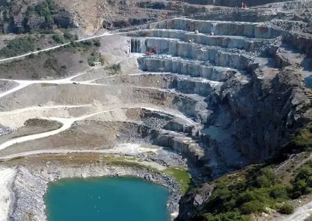 A color image of the many terraces of the Delabole Slate quarry with the blue-green groundwater lake at the bottom.