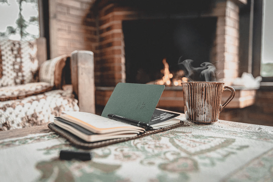 An open book on table in front of fireplace