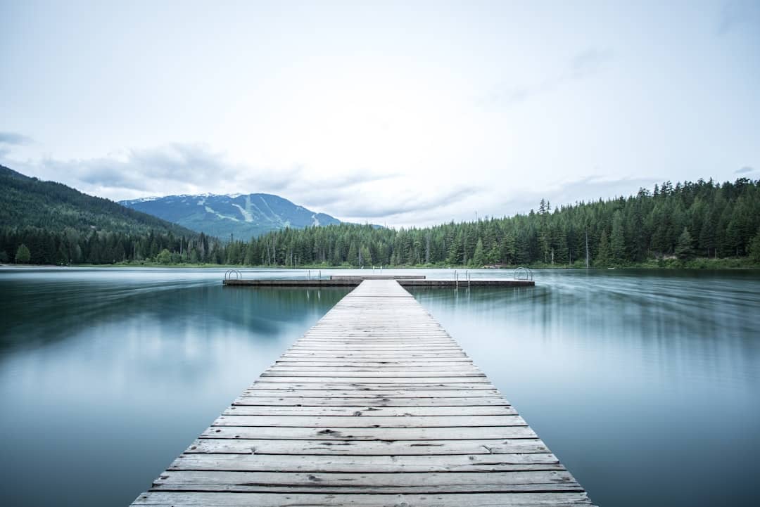 A dock leading to blue water lake in the mountains