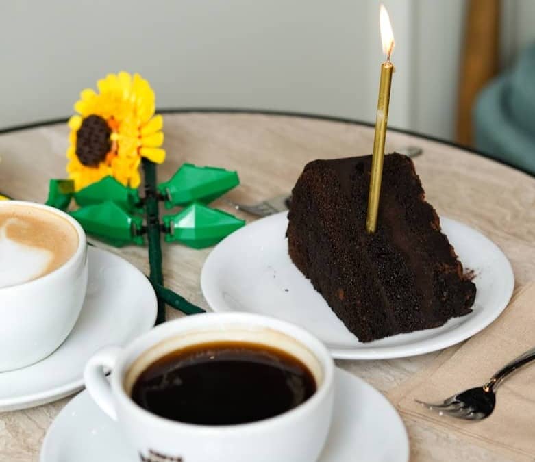 Coffee, cake, and a birthday candle are displayed.
