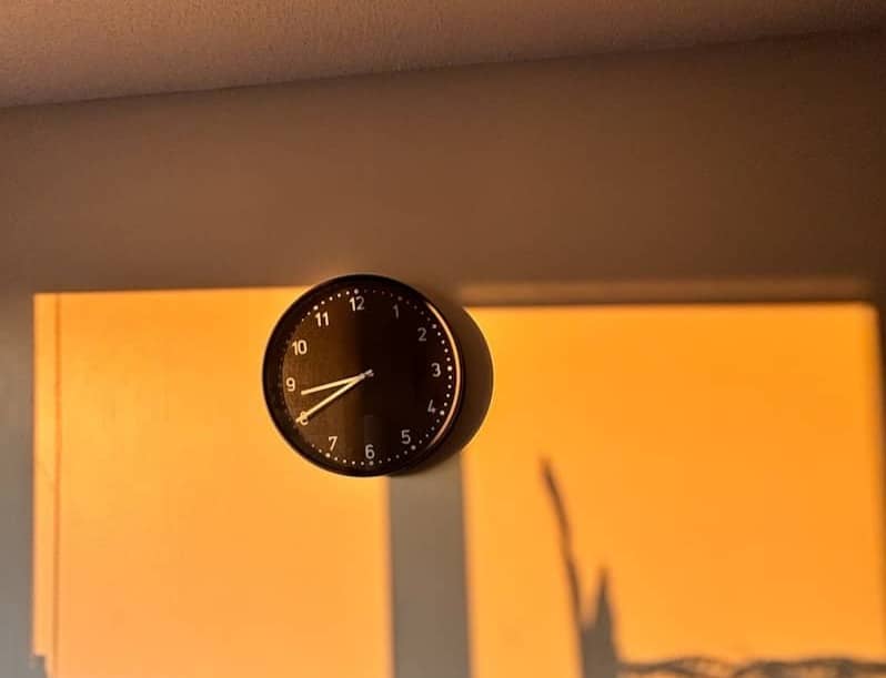 A clock hangs on a glowing orange wall.