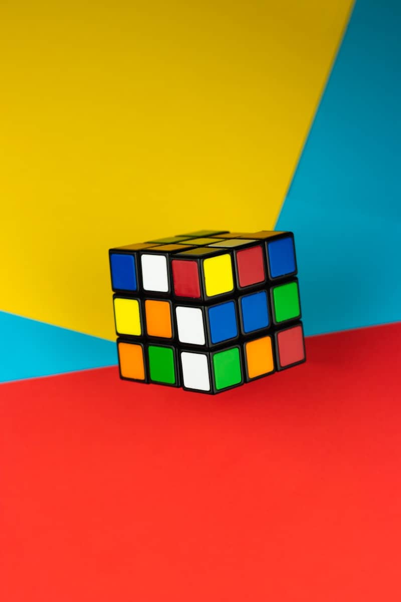 A rubik's cube rests on a colorful background.