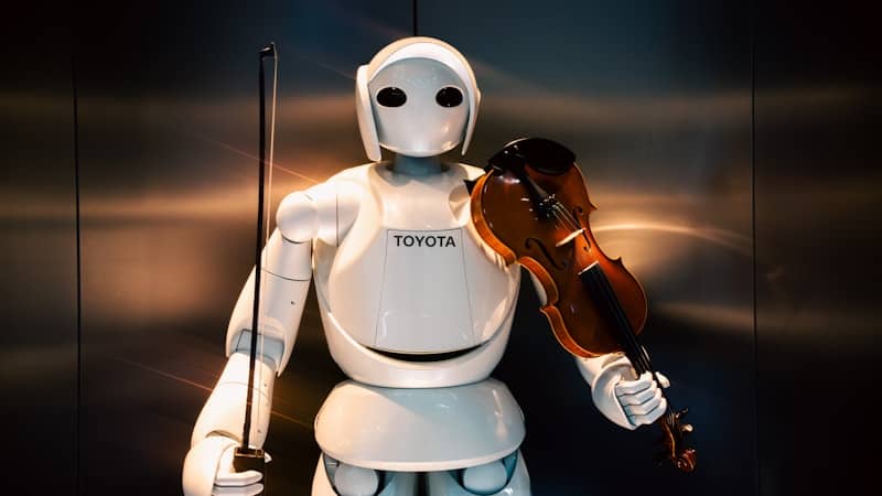 A white robot holding a violin and bow