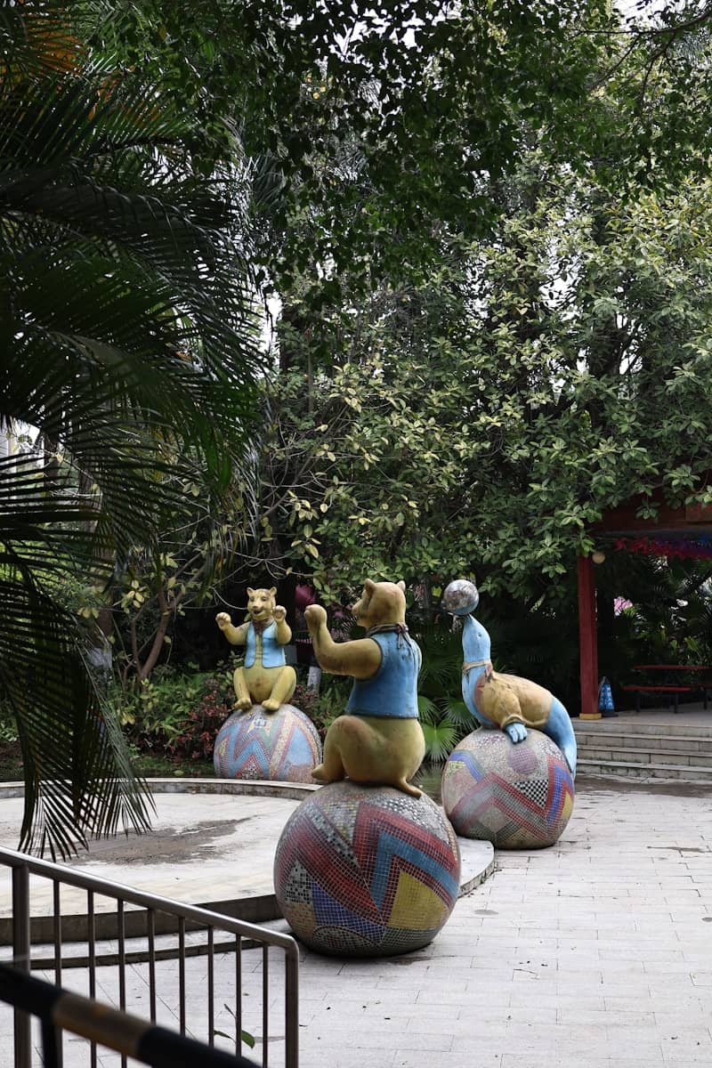 Bear statues sitting on colorful balls in a garden.