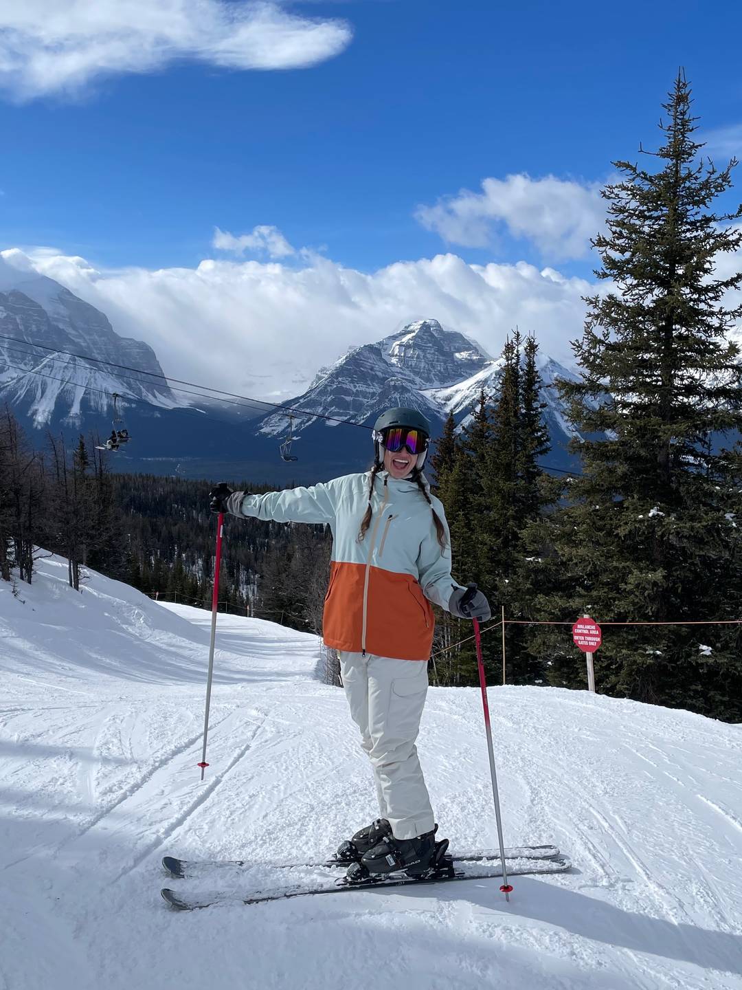 Skiier posing on snow at Lake Lousie Resort with mountains in the background