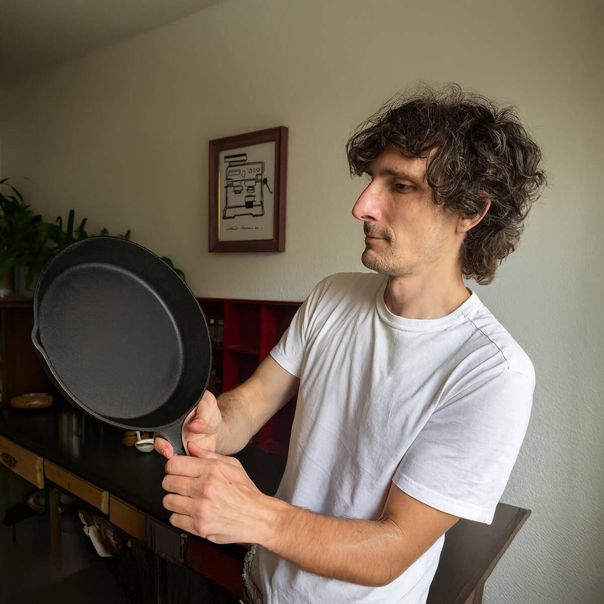 Hombre sosteniendo una sartén de hierro fundido en una cocina moderna, ejemplo de utensilio seguro y duradero según la ciencia en 2025.