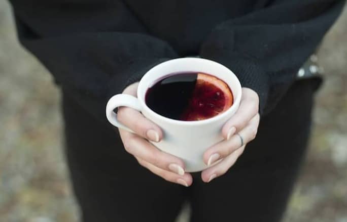 Hands holding a mug of mulled wine.