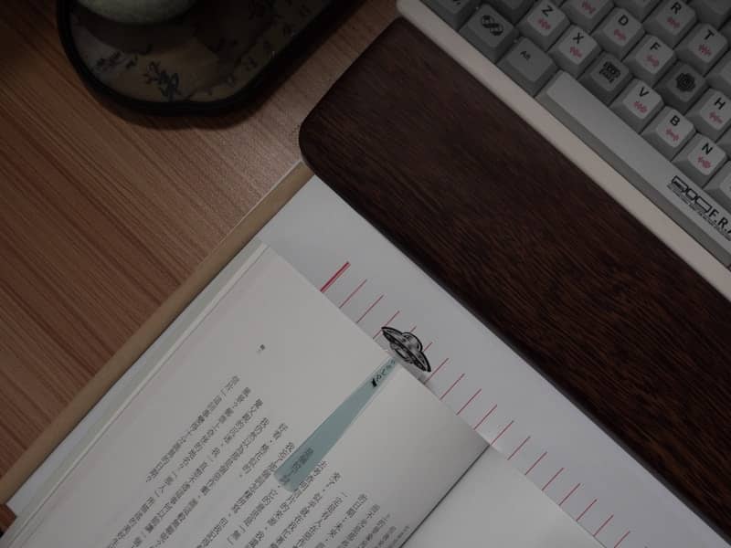Open book with bookmark next to keyboard