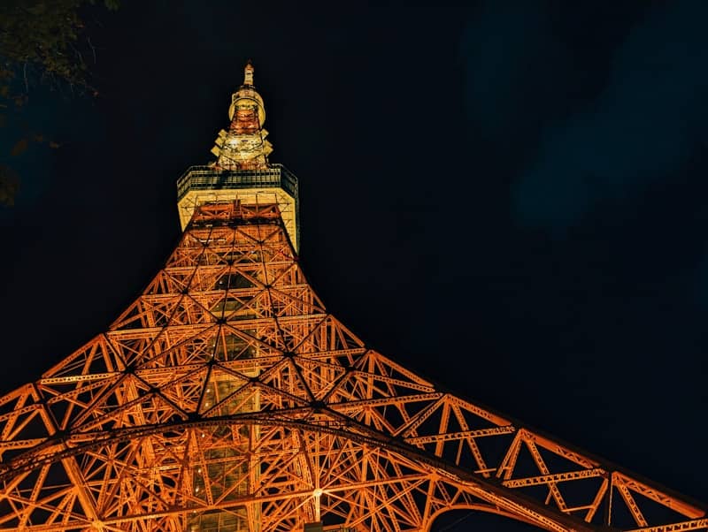 Tokyo tower illuminated at night against dark sky
