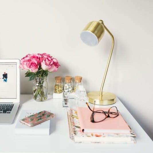 MacBook Air beside gold-colored study lamp and spiral books