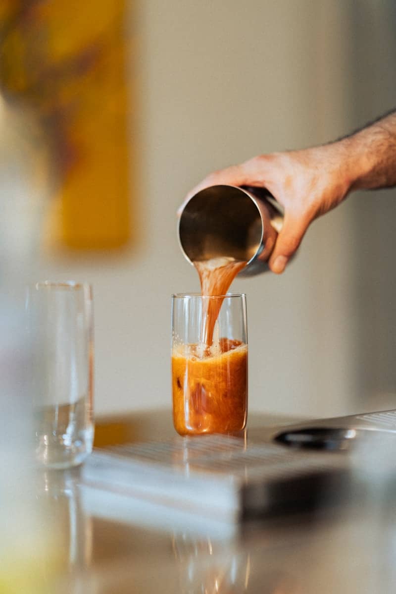 A person pouring something into a glass on a table