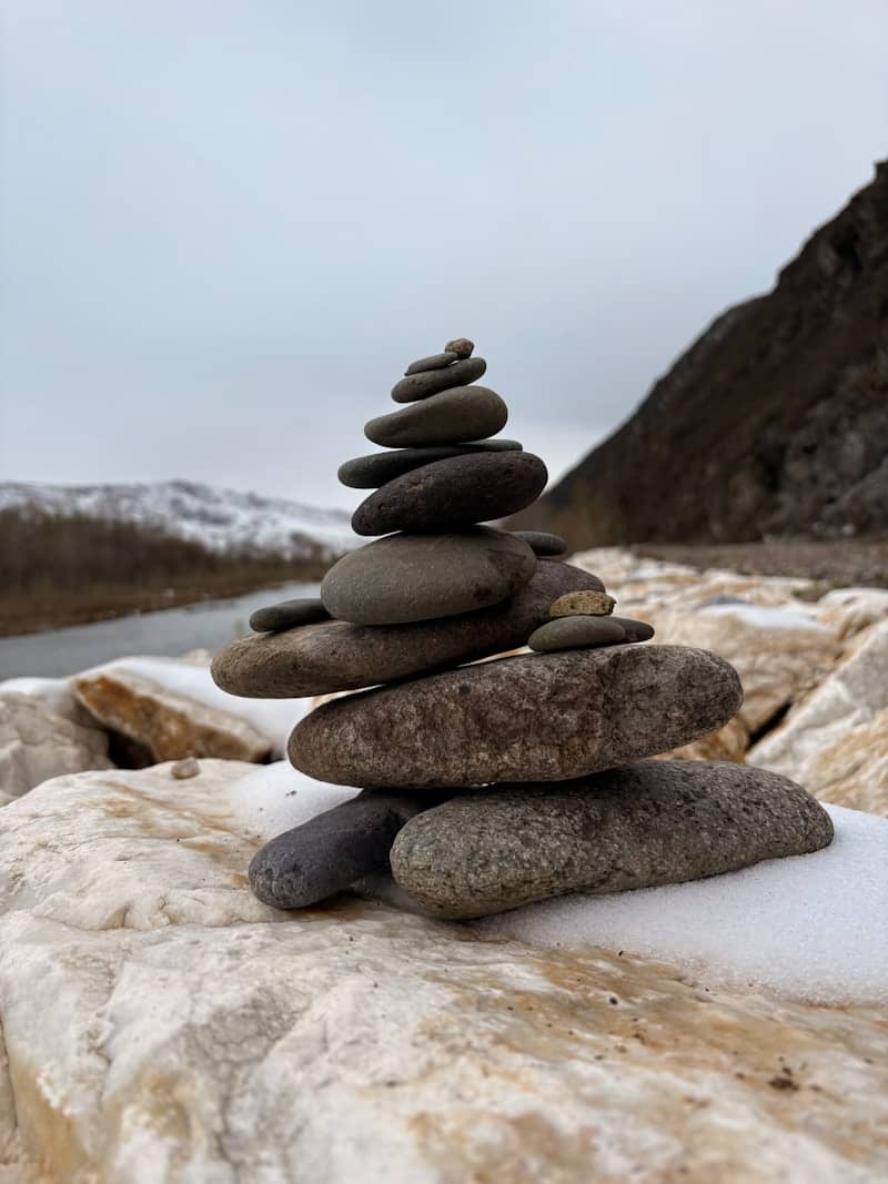 Stack of balanced stones on a snowy shore.