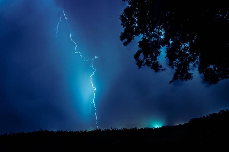 A lightning strike illuminates the dark sky.