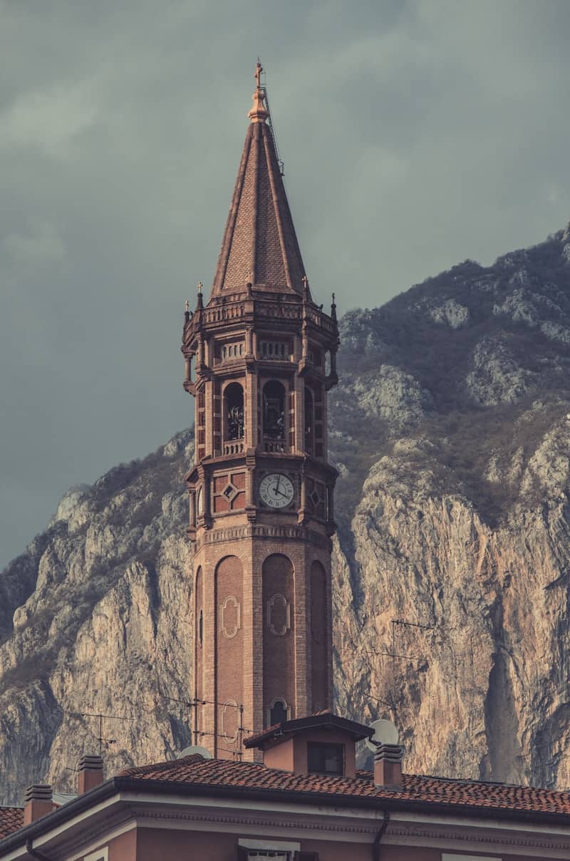 A tall church steeple faces a mountain.