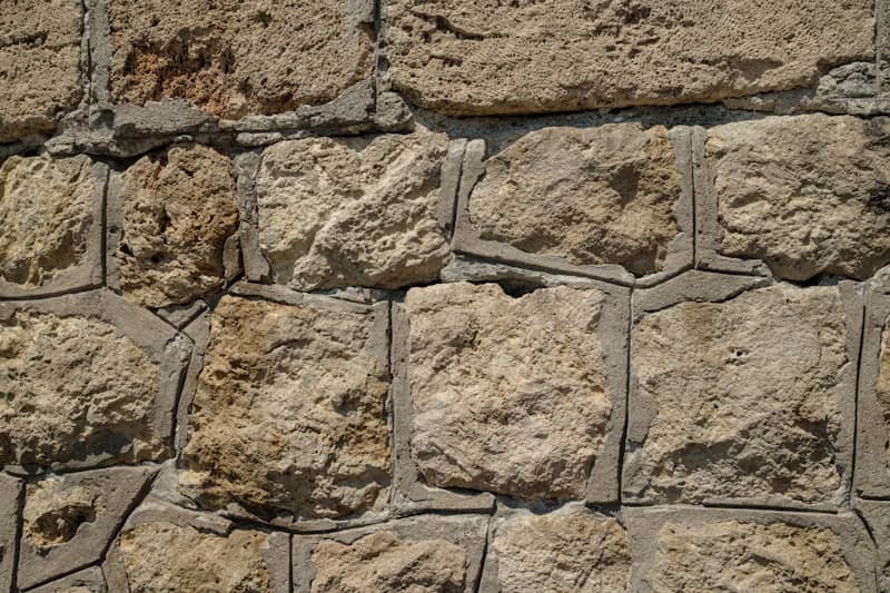 Rough textured stone wall with grey mortar