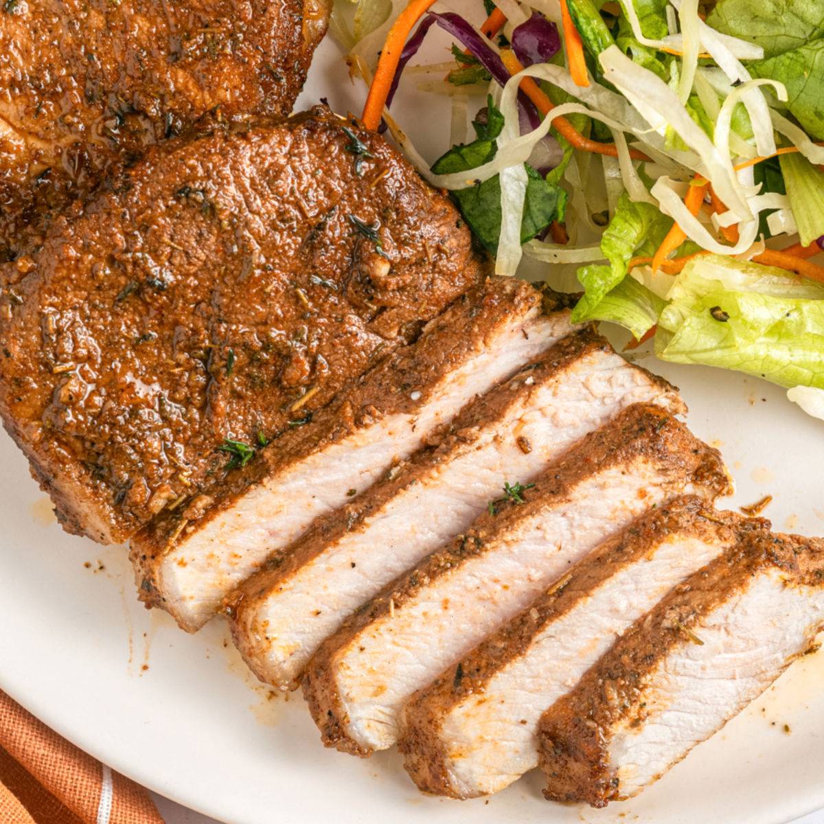 Sliced pork chops on a plate with salad