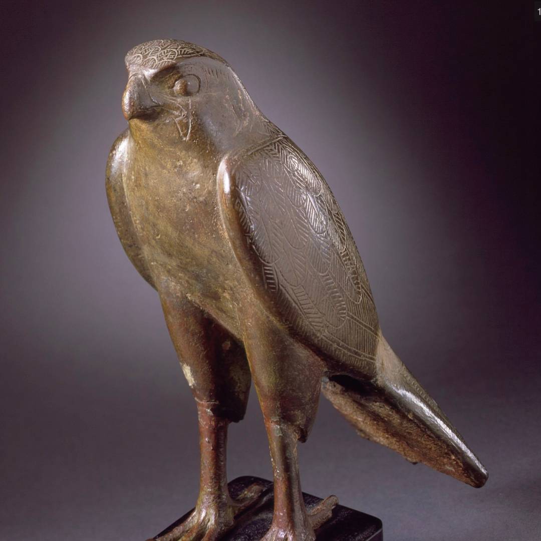 ancient Egyptian Horus as falcon statuette bronze on a grey background.