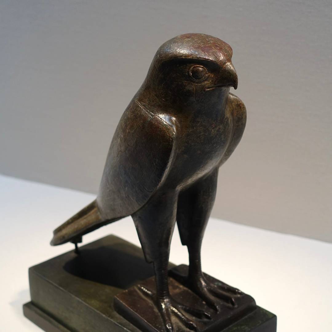 bronze silhouetted falcon statue with base against a lgrey backgroundight 