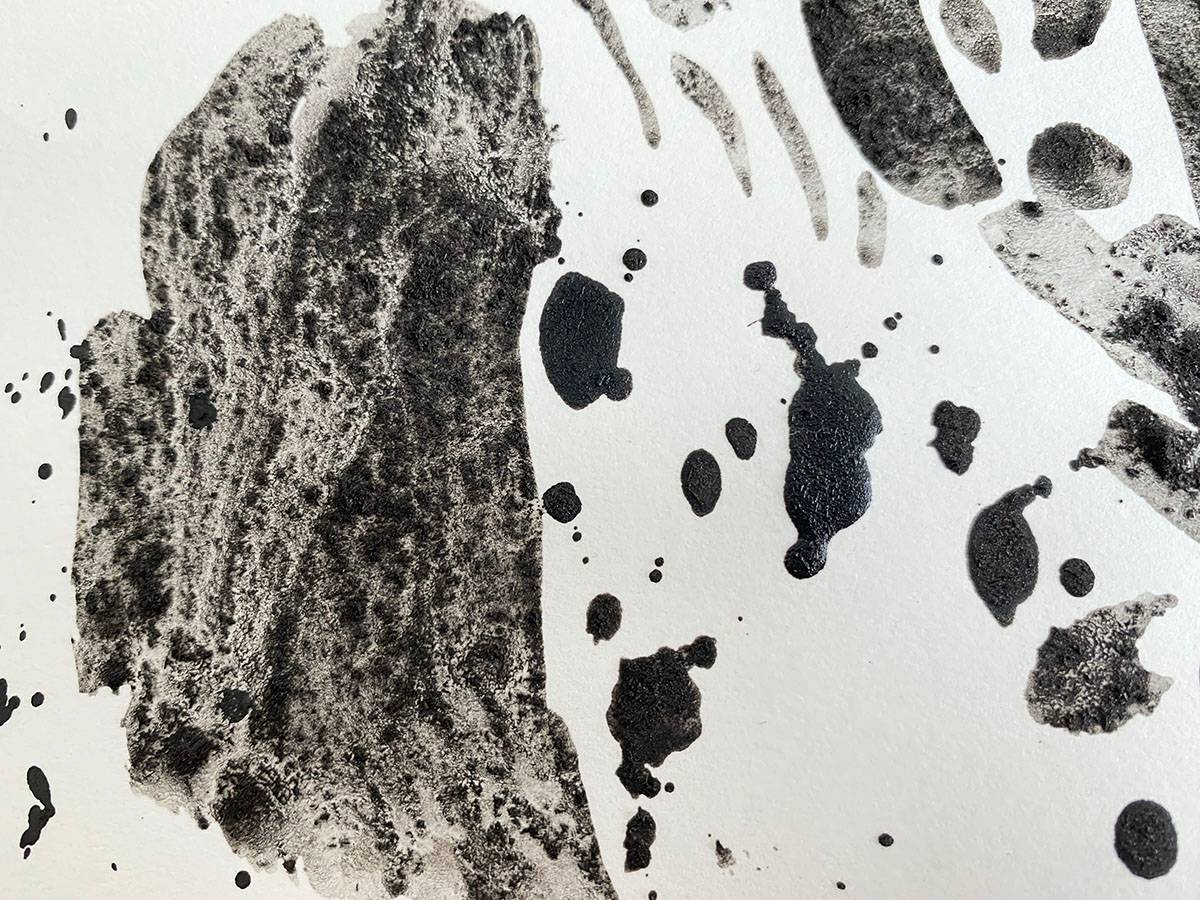 Granular black charcoal-paint, irregular marks on white paper.