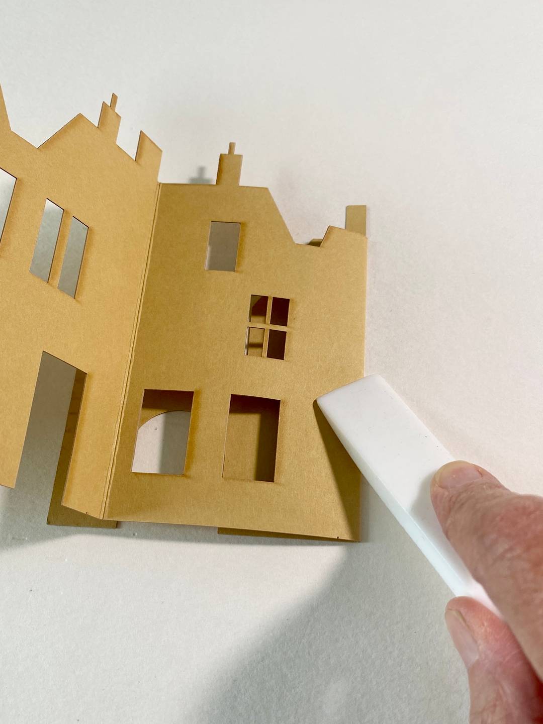 a person using a teflon folder to crease laser cut card.