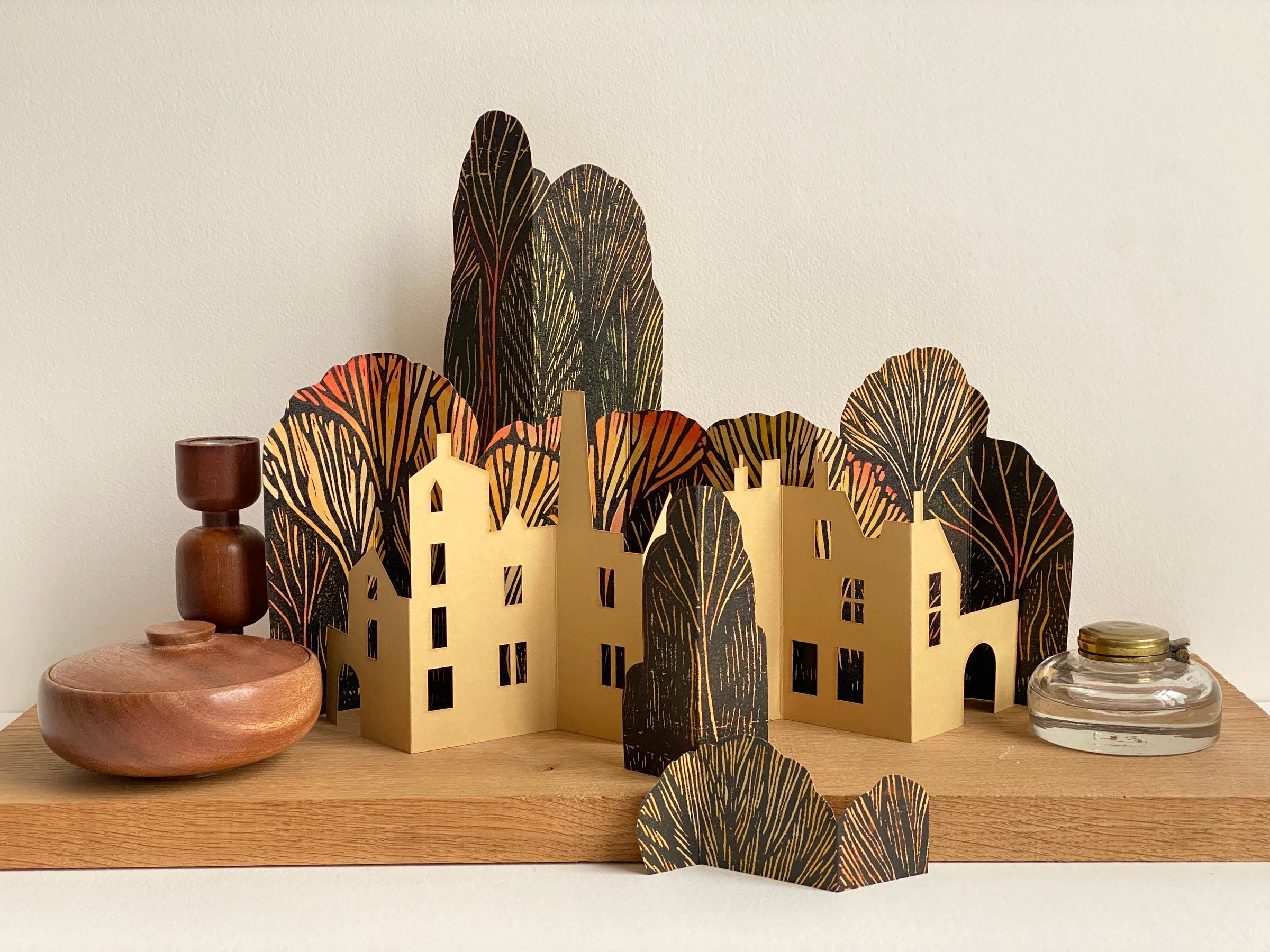 A table top paper sculpture of a townscape and woodland in Autumn