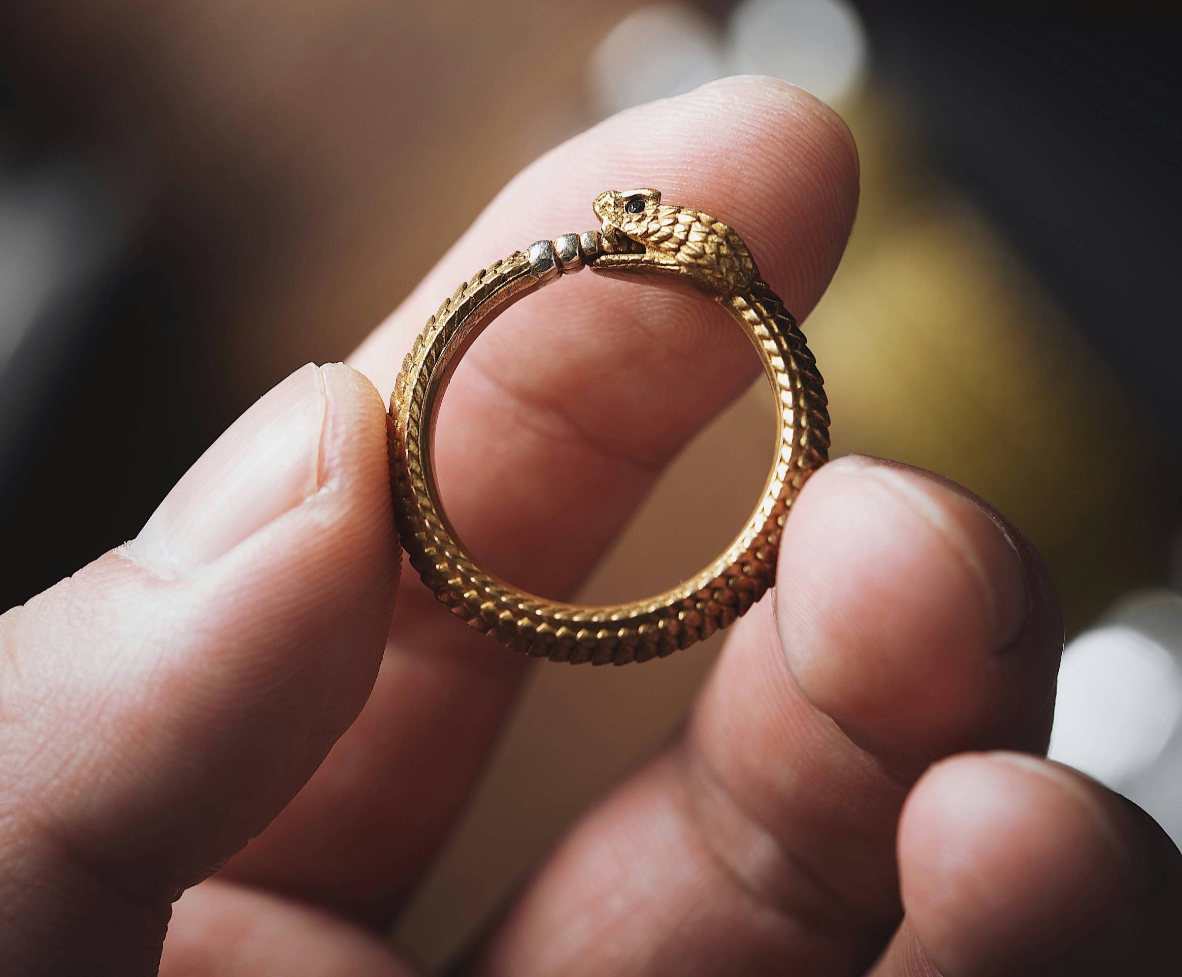 Fingers holding an ouroboros ring